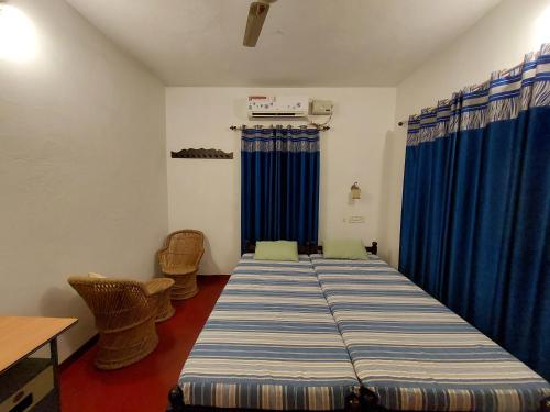 1 dormitorio con 1 cama grande y cortinas azules en Marari Beach Homestay, en Mararikulam
