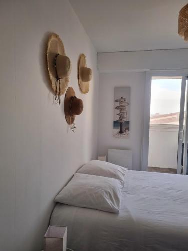 - une chambre avec un lit avec des chapeaux sur le mur dans l'établissement Eau Bleue d'Eden, à Saint-Hilaire-de-Riez