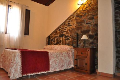 a bedroom with a bed and a stone wall at Casa rural rio yeguas in Azuel