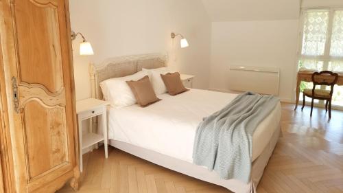um quarto com uma cama branca e piso em madeira em Gite du Four à Pain 4* - Le Domaine des Cyclamens em Verneuil-sur-Indre