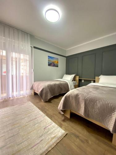 1 dormitorio con 2 camas y ventana grande en Nessii Apartment en Pristina