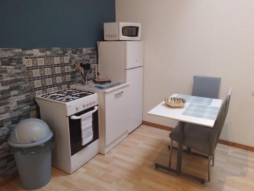 a small kitchen with a white stove and a table at 2 pièces cocooning in Saint-Claude