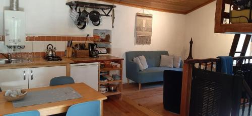 a kitchen and living room with a table and a chair at Casa Ribeira in Coentral das Barreiras