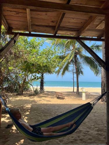 a man laying in a hammock on a beach at Breezy Beach Cabanas in Arugam Bay