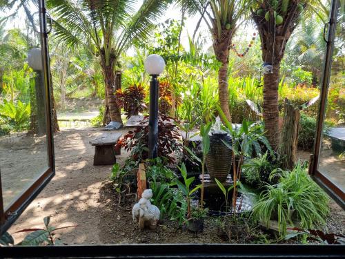 a garden with palm trees and a street light at Wind in the Wild Khao Yai in Nakhon Ratchasima