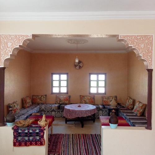 a living room with couches and a table and windows at Dar Brahim Resto Beds in Ouarzazate