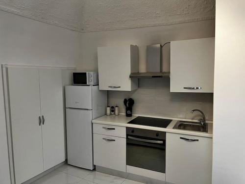 een keuken met witte kasten, een wastafel en een koelkast bij Marinella House in Napels