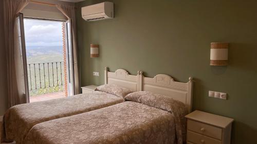 two beds in a bedroom with a large window at La Finca Mercedes in La Iruela