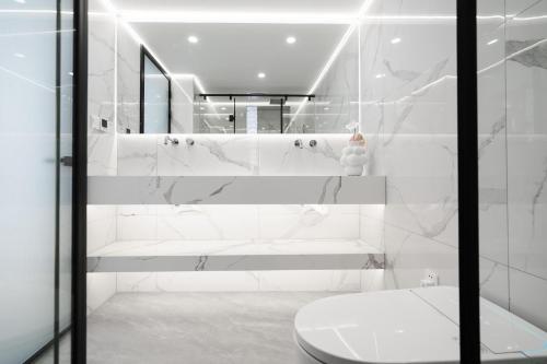 uma casa de banho branca com um WC e um chuveiro em Shanghai Downtown Yidu B&B - Near Jing'an Temple Metro Station em Xangai