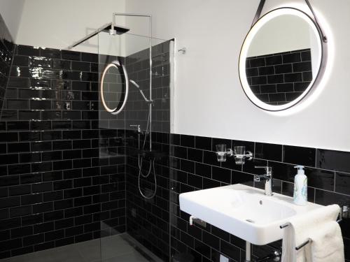 a black tiled bathroom with a sink and mirror at Loft Schottenau in Neusiedl am See