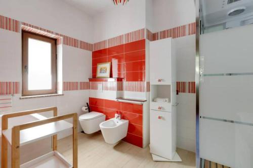 uma casa de banho vermelha e branca com um WC e um lavatório em Agrifoglio B&B con giardino em Aritzo