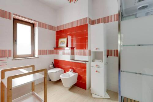 a red and white bathroom with a toilet and a sink at Agrifoglio B&B con giardino in Aritzo