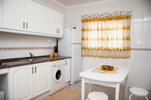 a kitchen with white cabinets and a white table at Os Apartamentos A Ramos na Praia da Galé Estão inserido em Condomínio com PISCINA, Fica apenas a 350 Metros da Praia da Galé - Apartamentos com Ar Condicionado tanto nos Quartos como na Sala, Smart TV com Prime Vídeo e Cozinha Completa in Albufeira