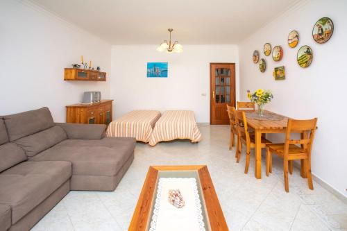 a living room with a couch and a table at Os Apartamentos A Ramos na Praia da Galé Estão inserido em Condomínio com PISCINA, Fica apenas a 350 Metros da Praia da Galé - Apartamentos com Ar Condicionado tanto nos Quartos como na Sala, Smart TV com Prime Vídeo e Cozinha Completa in Albufeira