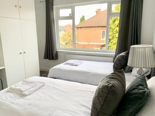 1 dormitorio con 2 camas y ventana en Immaculate 3-Bed Travel nest unavailable, en Mánchester