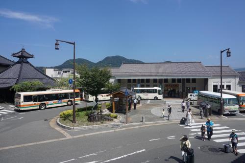 a group of people crossing a street in front of a bus station at Morizuya in Toyooka