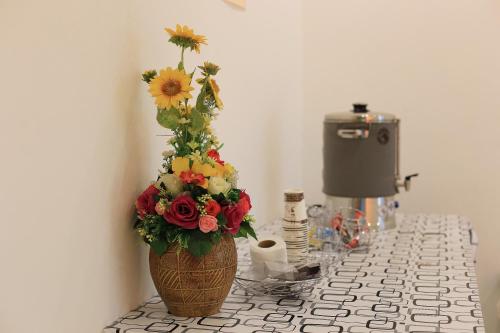 a vase with a flower arrangement on a counter at The Original Orange Hotel in Nakhon Si Thammarat