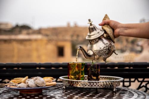 a person is holding a tea kettle on a table at Dar alhaja rahma in Fès
