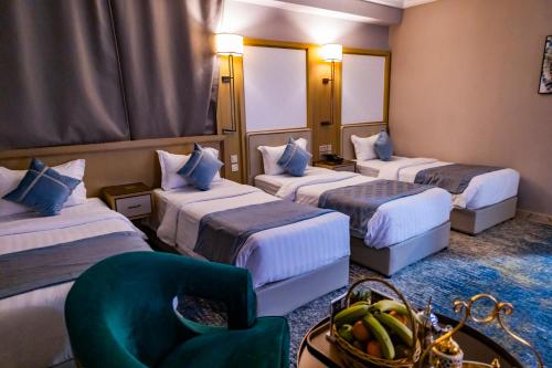una camera d'albergo con tre letti e una sedia di فندق وقف عثمان بن عفان a Medina