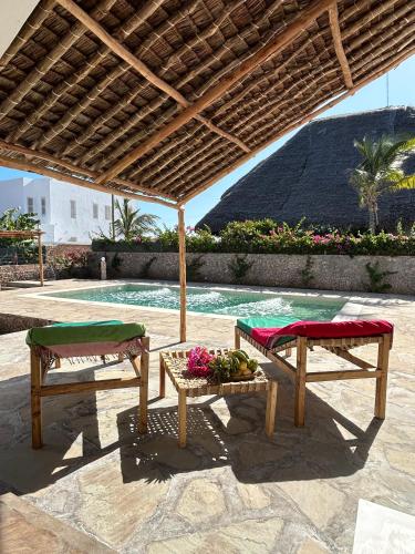 two chairs and a table under a wooden umbrella at Nyumbani Tamu in Watamu