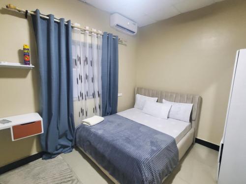 Tammy Homes stay في دار السلام: غرفة نوم صغيرة مع سرير مع ستائر زرقاء