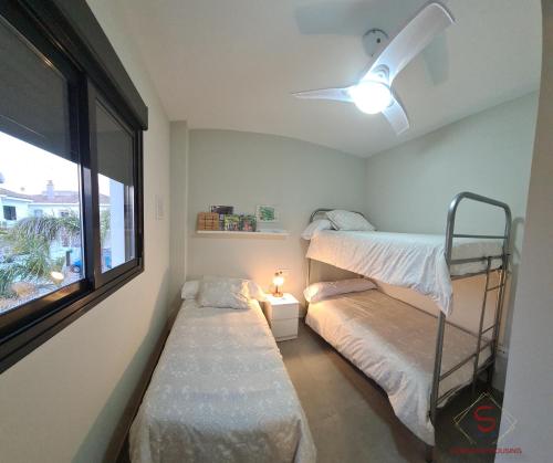 a bedroom with two bunk beds and a window at Arenas de Doñana amplio apartamento frente del mar in Sanlúcar de Barrameda
