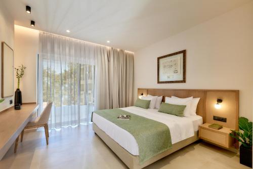 a bedroom with a bed and a desk and a window at Inea Sole Boutique Hotel in Kato Daratso