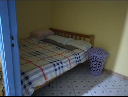 een kleine slaapkamer met een bed en een vuilnisbak bij Gill's Crib in Maseno