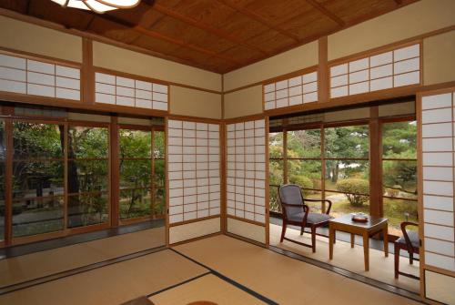an empty room with windows and a table and chairs at Sansuien in Yamaguchi
