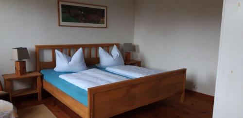 a bedroom with a wooden bed with white pillows at 130qm-grosse-Ferienwohnung-am-Naturschutzgebiet-15-Min-bis-zum-Stettiner-Haff-PKW in Bugewitz