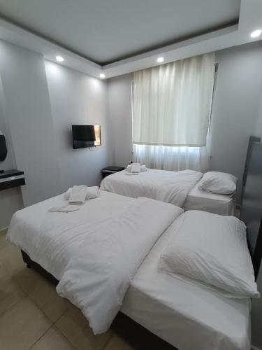 um quarto com 3 camas e lençóis brancos em Hermes Otel em Edirne