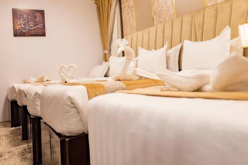 a row of white beds in a room at Odst Al Madinah Hotel in Al Madinah