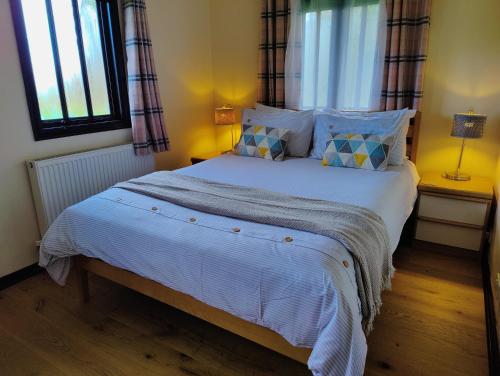 a bedroom with a large white bed with two windows at Parsonage Barn Annex in Winchelsea