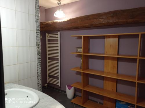 - une salle de bains avec des étagères en bois à côté d'une baignoire dans l'établissement Maison spacieuse et calme à la campagne, à Saint-Denis-sur-Sarthon
