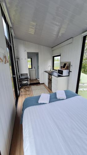 a bedroom with a large white bed and a kitchen at Under the Vines in Earnscleugh in Earnscleugh