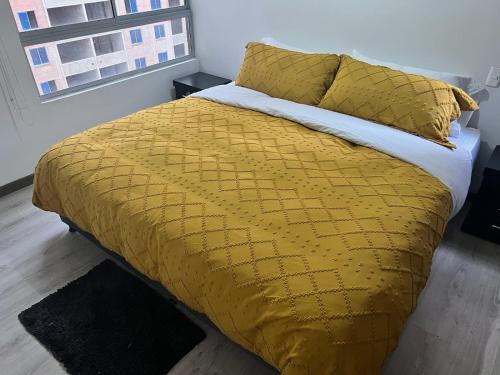 Cama amarilla con edredón y almohadas amarillos en apartamento privado, en Bogotá