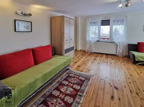a living room with a red couch and wooden floors at Koniecznie Róża in Karpacz