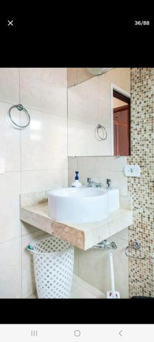 a bathroom with a white sink and a mirror at SUITES E QUARTOS CASA PAPAI NOEL in Campos do Jordão