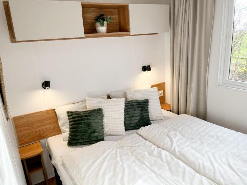 a bedroom with a white bed with green pillows at Ocean Garden Chalet Renesse in Renesse