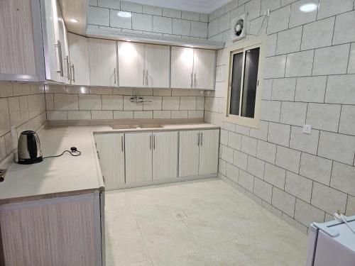 eine Küche mit weißen Schränken und einer Arbeitsplatte in der Unterkunft شقق مفروشة in Medina
