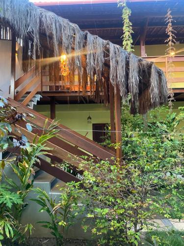 a balcony with a straw roof and a wooden bench at Pousada Águas de Tamandaré in Tamandaré