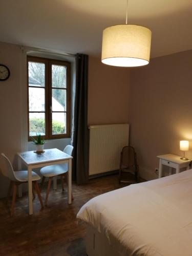 a bedroom with a bed and a table and a window at A La Halte Des Gorges in Nevy-sur-Seille