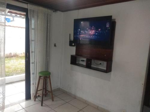 TV en la pared en una habitación con taburete en Casa Praia NAVEGANTES GRAVATÁ en Navegantes