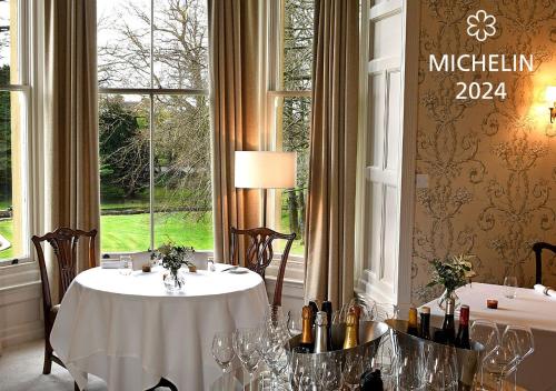 a dining room with two tables with wine glasses at Farlam Hall Hotel & Restaurant in Brampton