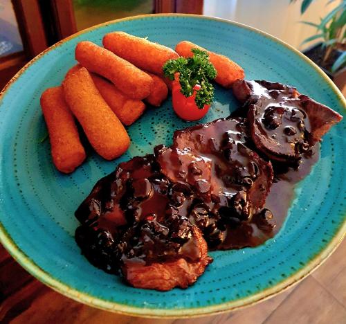 a blue plate with meat and carrots on a table at Hotel & Restoran Dvorac Gjalski in Zabok