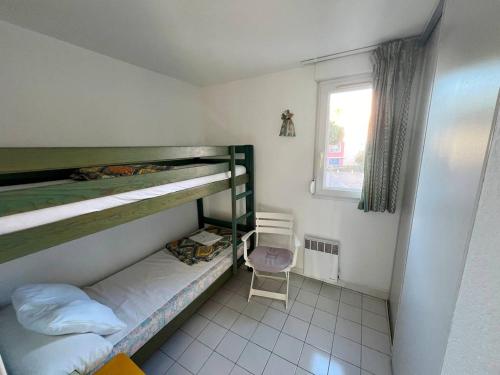 - une chambre avec 2 lits superposés et une chaise dans l'établissement SAVANNA BEACH II Joli appartement 3 pièces avec piscine Rochelongue Cap d'Agde, au Cap d'Agde