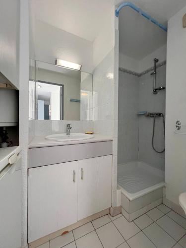 une salle de bain blanche avec un lavabo et une douche dans l'établissement SAVANNA BEACH II Joli appartement 3 pièces avec piscine Rochelongue Cap d'Agde, au Cap d'Agde