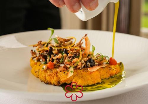 a person pouring sauce on a plate of food at Farlam Hall Hotel & Restaurant in Brampton