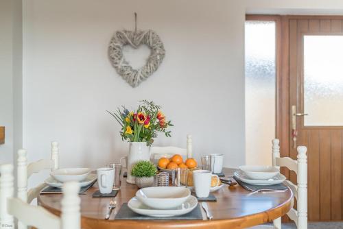 a dining room table with a heart ornament on the wall at Hafod-Llecheiddior in Brynkir
