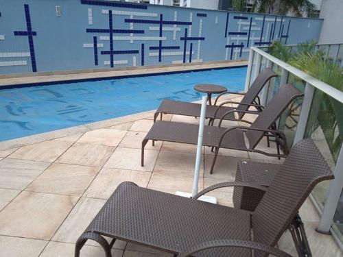 um grupo de cadeiras e uma mesa ao lado de uma piscina em Ap loft Belvedere fronte shopping BH em Belo Horizonte